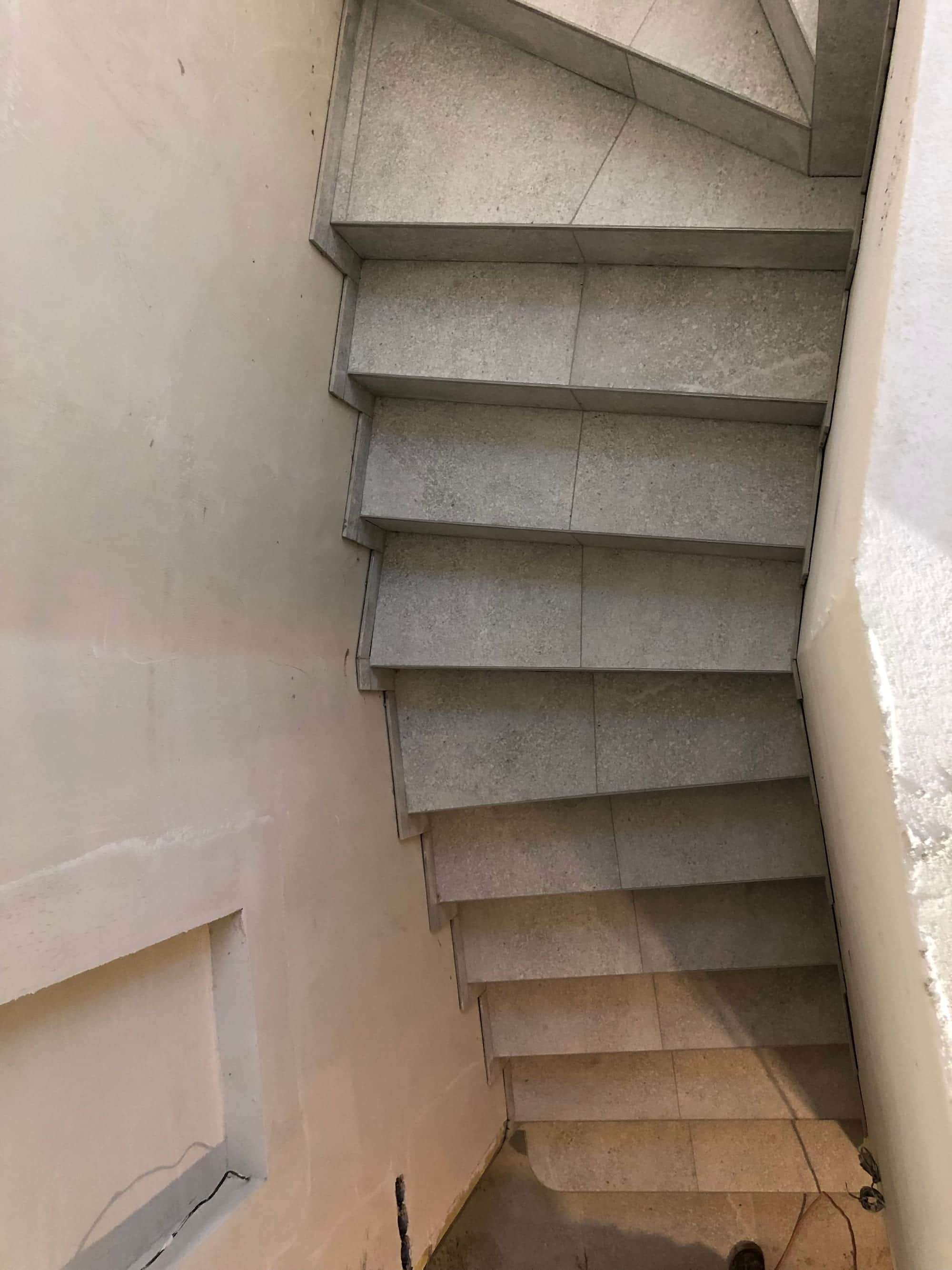 Točité schodisko s obloženými klinovými stupňami v svetlom kamennom dekore