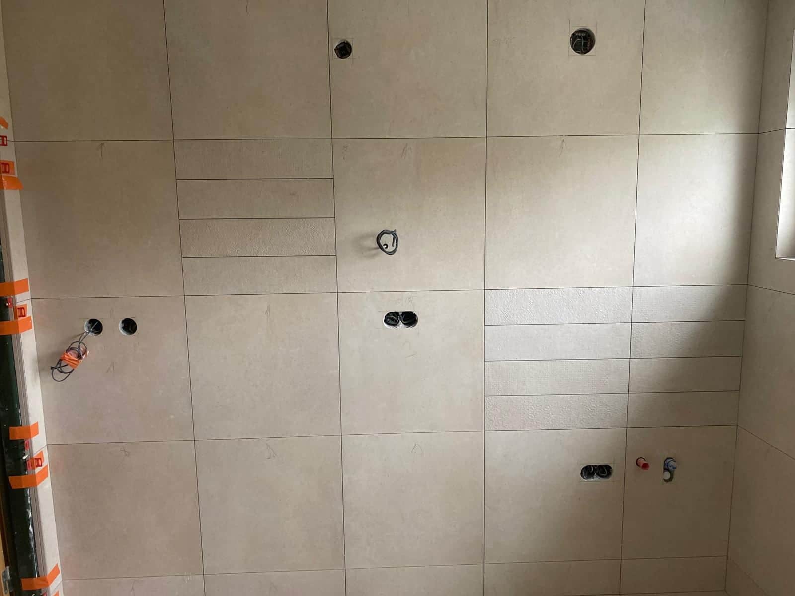 Prestupy pre batériu a sprchu vyrezané v obklade, rohová lišta chránená páskou
